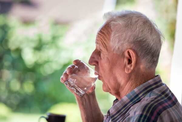 Advanced Care senior drinks a glass of water